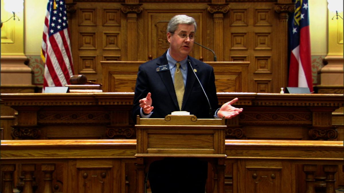 Dr. Cecil P. Staton addressing the Georgia State Senate from the well, with the U.S. and Georgia flags behind him